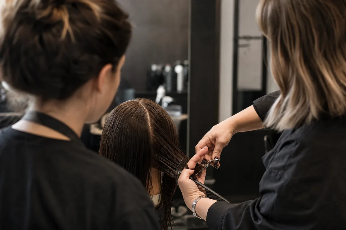 Apprenti coiffeur en formation observant un geste technique en salon